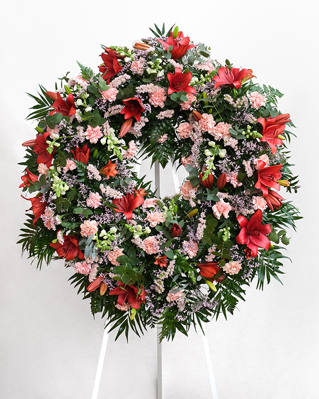 Corona amb lilium vermell, clavell rosa, conillet blanc, limonium rosa, estetice rosa clar, chico, leder i eucaliptus